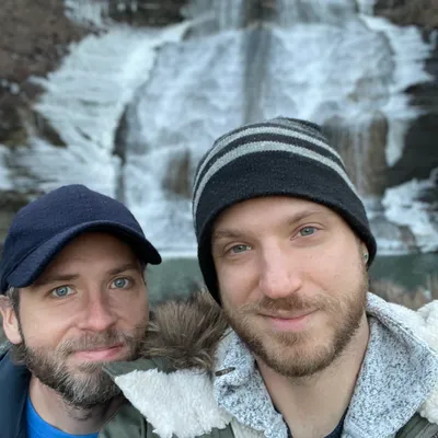 A picture of two men in front of a waterfall in winter