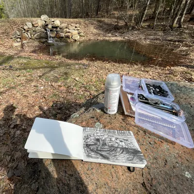 A picture of a notebook with charcoal drawings on a rock